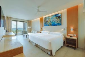 a bedroom with a large white bed with a painting on the wall at Barceló Maya Riviera - All Inclusive Adults Only in Xpu Ha