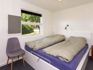 ein Schlafzimmer mit einem Bett, einem Stuhl und einem Fenster in der Unterkunft Holiday home Roslev XXX in Roslev