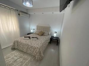 a white bedroom with a bed and a window at Apartamento playa Fuengirola centro paseo marítimo in Fuengirola