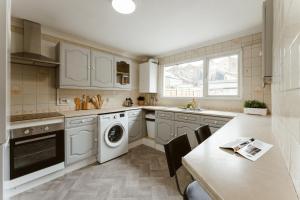 una cocina con electrodomésticos blancos y una mesa con sillas. en CanningTown Double Rooms - 20, en Londres