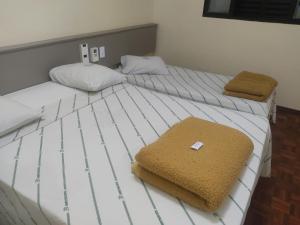 two beds in a bedroom with white sheets and towels at Blanco Palace Hotel in São José dos Campos