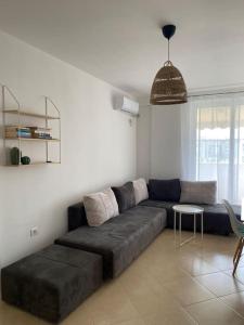 ein Wohnzimmer mit einem großen Sofa und einem Tisch in der Unterkunft The Flip-Flop Apartment in Shëngjin