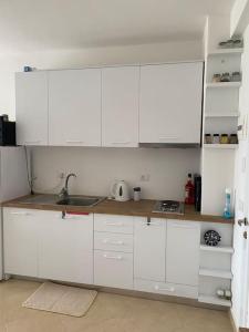 una cocina con armarios blancos y fregadero en The Flip-Flop Apartment, en Shëngjin