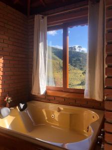 a bath tub in a bathroom with a window at Recanto João de barro in Visconde De Maua