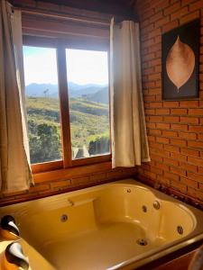 uma banheira na casa de banho com uma janela em Recanto João de barro em Visconde de Mauá