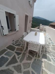 d'une table et de chaises blanches sur un balcon. dans l'établissement Maison de charme proche Bastia, à Prunelli-di-Casacconi