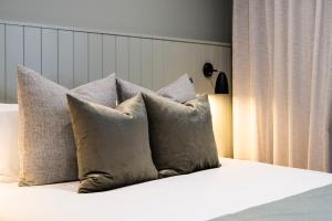una pila de almohadas sentadas en una cama con en Aden Hotel Mudgee, en Mudgee