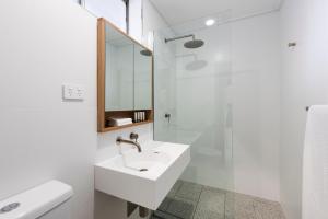 biała łazienka z umywalką i prysznicem w obiekcie Aden Hotel Mudgee w mieście Mudgee