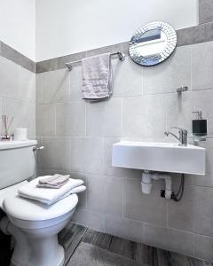 a bathroom with a sink and a toilet and a mirror at Cheerful 3Bed Spacious Holiday Home in Abercynon