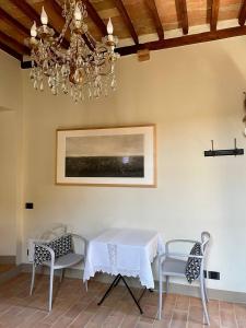 een eetkamer met een tafel en stoelen en een kroonluchter bij Locanda In Piazzetta - Casa in Centro Storico in San Quirico dʼOrcia