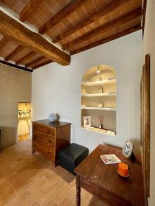 a living room with a wooden table and a wooden shelf at Locanda In Piazzetta - Casa in Centro Storico in San Quirico dʼOrcia