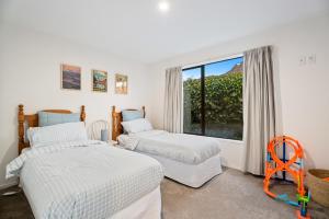 a bedroom with two beds and a large window at Frankton Favourite - Queenstown Holiday Home in Queenstown