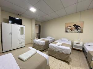 a hospital room with four beds and a tv at Hotel La Capilla - Suites & Apartments San Benito in San Salvador