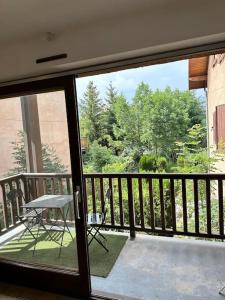een glazen deur met een tafel op een balkon bij Charmant appartement in Briançon