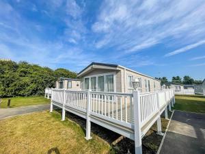a mobile home with a white railing on a yard at Beautiful 8 Berth Caravan With Decking At Broadland Sands In Suffolk Ref 20017cv in Hopton on Sea