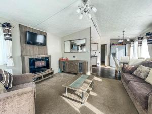 a living room with a couch and a tv and a table at Beautiful 8 Berth Caravan With Decking At Broadland Sands In Suffolk Ref 20017cv in Hopton on Sea