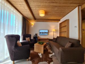 a living room with a couch and chairs and a tv at CHALET ASKALA JASNÁ in Demanovska Dolina