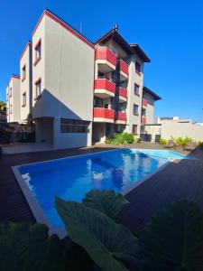 a building with a swimming pool in front of a building at Verdes Pássaros Apart Hotel in Florianópolis
