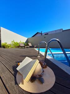 a hat and sunglasses and a book on a deck at Verdes Pássaros Apart Hotel in Florianópolis