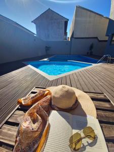 a hat and sunglasses and a book next to a swimming pool at Verdes Pássaros Apart Hotel in Florianópolis