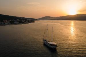 ein Boot, das bei Sonnenuntergang im Wasser sitzt in der Unterkunft Apartments by the sea Arbanija, Ciovo - 11041 in Trogir