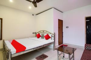 a bedroom with a bed with white walls and red pillows at OYO Flagship Mango Leaf Hotel & Restaurant in Baharampur