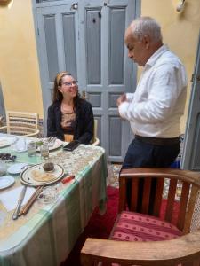 a man standing next to a woman sitting at a table at La Maison Haute Larache Morocco in Larache