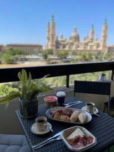 einen Tisch mit einem Teller Essen auf dem Balkon in der Unterkunft Apartamento Con Vistas Al Pilar con Aparcamiento privado in Saragossa