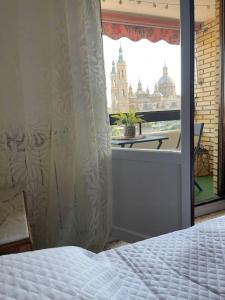 een slaapkamer met een bed en een raam met uitzicht bij Apartamento Con Vistas Al Pilar con Aparcamiento privado in Zaragoza