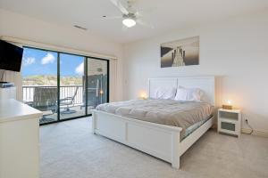 a white bedroom with a bed and a balcony at On a Point in Lake Ozark