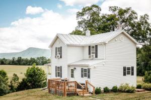 ein weißes Haus mit einer Terrasse und Bergen im Hintergrund in der Unterkunft Mountain View Farmhouse in Luray, Family Friendly in Luray