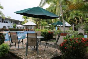 a table and chairs with an umbrella next to a pool at Tropical Bliss Pool Wi-Fi BBQ Near Quepos Manuel Antonio in Quepos