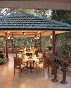 a wooden pavilion with tables and chairs on a patio at The Oberoi Bengaluru in Bengaluru