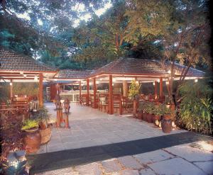 a pavilion with tables and potted plants and trees at The Oberoi Bengaluru in Bengaluru