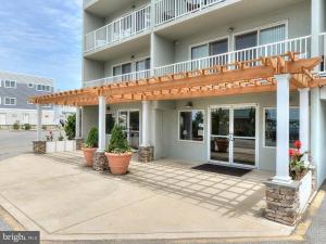 a building with a porch with potted plants in front of it at Town of Dewey Beach - 100 Collins Ave, Unit #103 in Dewey Beach