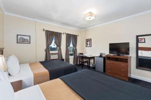 a hotel room with two beds and a flat screen tv at Hollywood Historic Hotel in Los Angeles