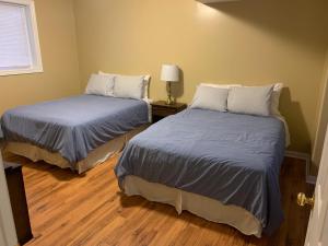 two beds in a small room with wood floors at Wu Wu's Cabins in Wasaga Beach