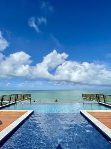 a swimming pool with the ocean in the background at Apartamento Praia de Carapibus in Conde