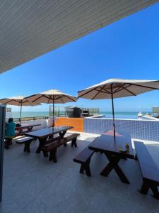 a group of picnic tables with umbrellas on a roof at Apartamento Praia de Carapibus in Conde