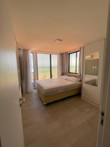 a bedroom with a bed and a view of the ocean at Apartamento Praia de Carapibus in Conde