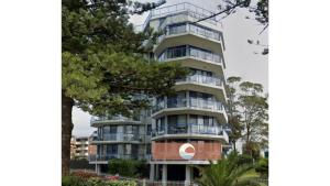 an apartment building with balconies and a tree at Heritage unit 101 in Tuncurry