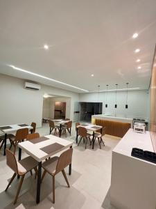 a dining room with tables and chairs and a kitchen at Pousada Paraíso in Teresina