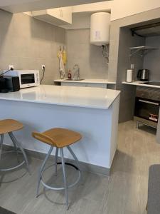 a kitchen with a white counter and two stools at Lisboa - Arroios Central Apartment in Lisbon