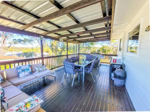 a porch with a couch and a table on a deck at The Perfect Holiday Home in Sussex inlet