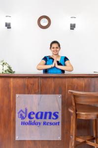 a woman standing behind a desk with a sign at Jeans Holiday Resort in Kandy