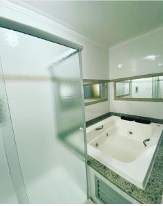 La salle de bains est pourvue d'une baignoire et d'une porte de douche en verre. dans l'établissement Grande Hotel, à Paranavaí
