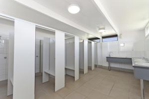 een grote badkamer met witte kraampjes en een wastafel bij Gum Tree Caravan Park in Port Fairy +27 foto's