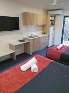 una camera d'albergo con due letti e una cucina di Abode37 Motel Emerald a Emerald