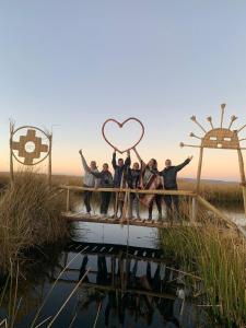 un grupo de personas sosteniendo un signo de corazón en un puente en Uros Lodge Lover Titiqaqa, en Puno