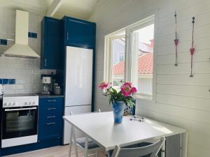 eine Küche mit blauen Schränken und einem Tisch mit Blumen darauf in der Unterkunft Holiday home BRäNNö in Brännö